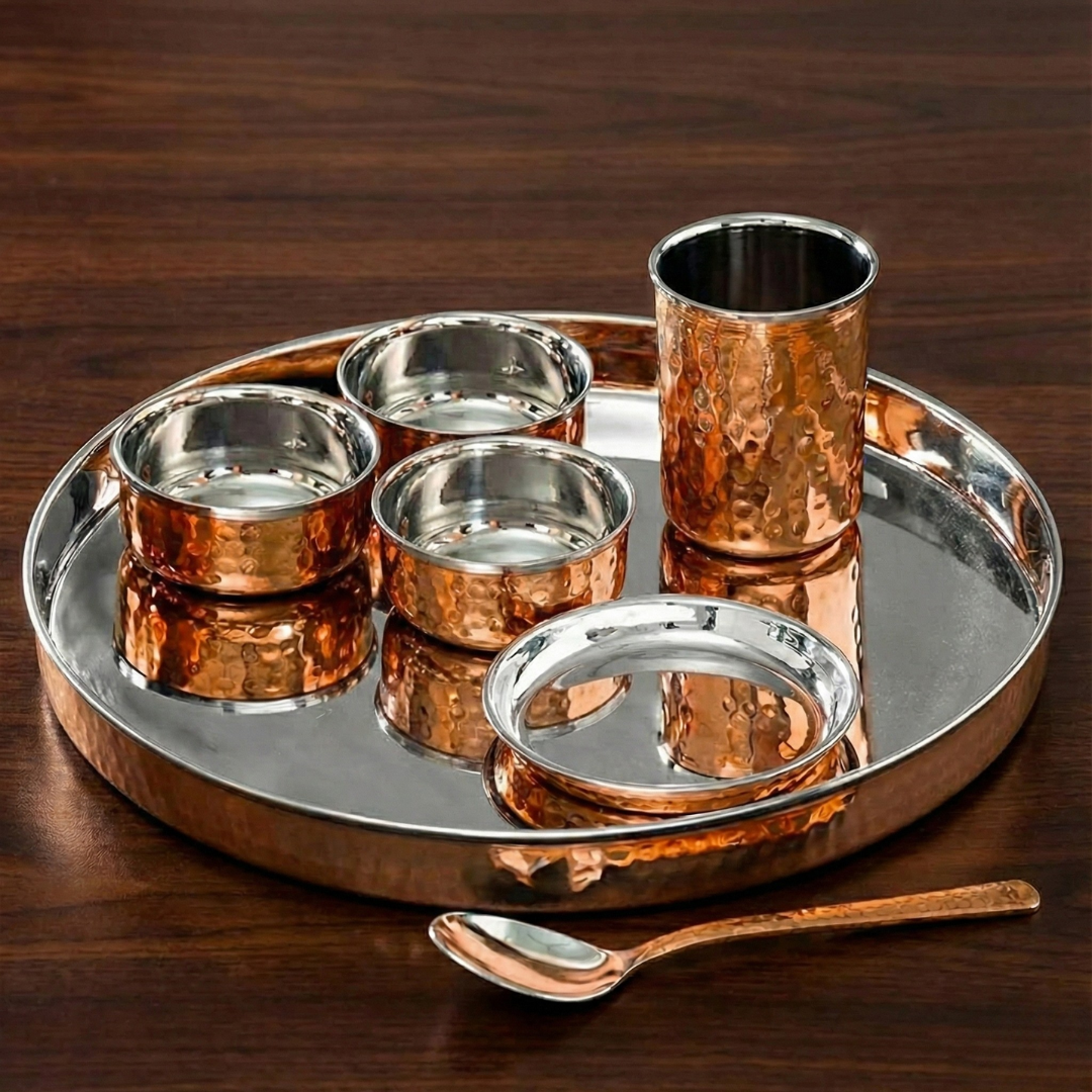 An elegant hammered Copper thali set featuring a round plate with inner steel coating with three small katoris, a  GLASS, and a spoon.
