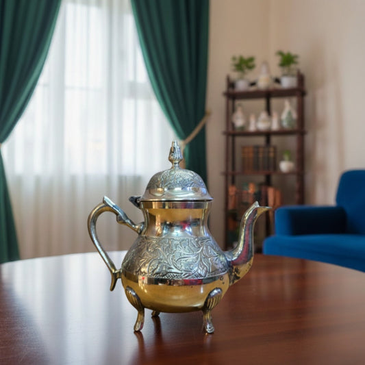 Handcrafted brass teapot with intricate floral engravings, domed lid, curved spout, and ornate feet on wooden table for home décor or tea service